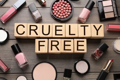 Photo of Flat lay composition with words Cruelty Free and different cosmetic products not tested on animals against wooden background