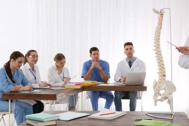 Medical students studying human spine structure in classroom