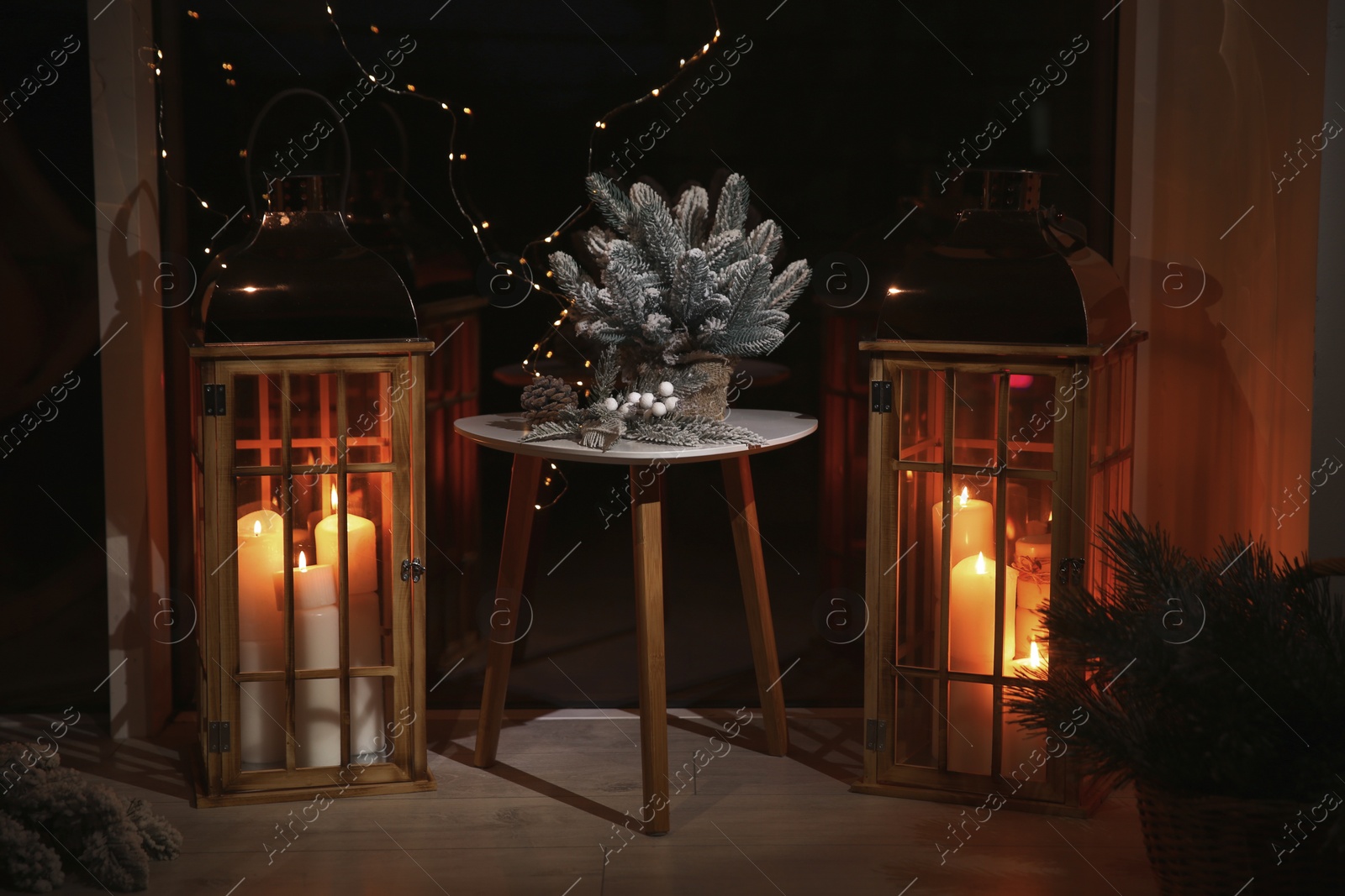 Photo of Beautiful lanterns with burning candles and Christmas decor in room. Interior design