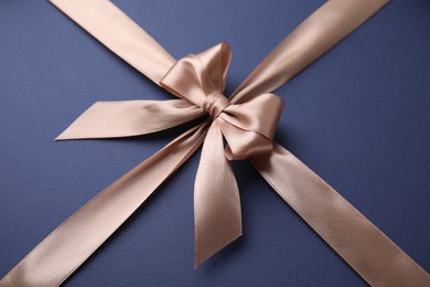 Beige satin ribbon with bow on blue background
