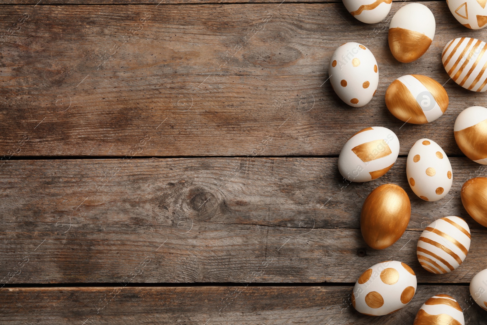 Photo of Traditional Easter eggs decorated with golden paint on wooden background, top view. Space for text