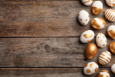 Traditional Easter eggs decorated with golden paint on wooden background, top view. Space for text