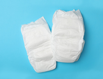 Photo of Baby diapers on light blue background, flat lay