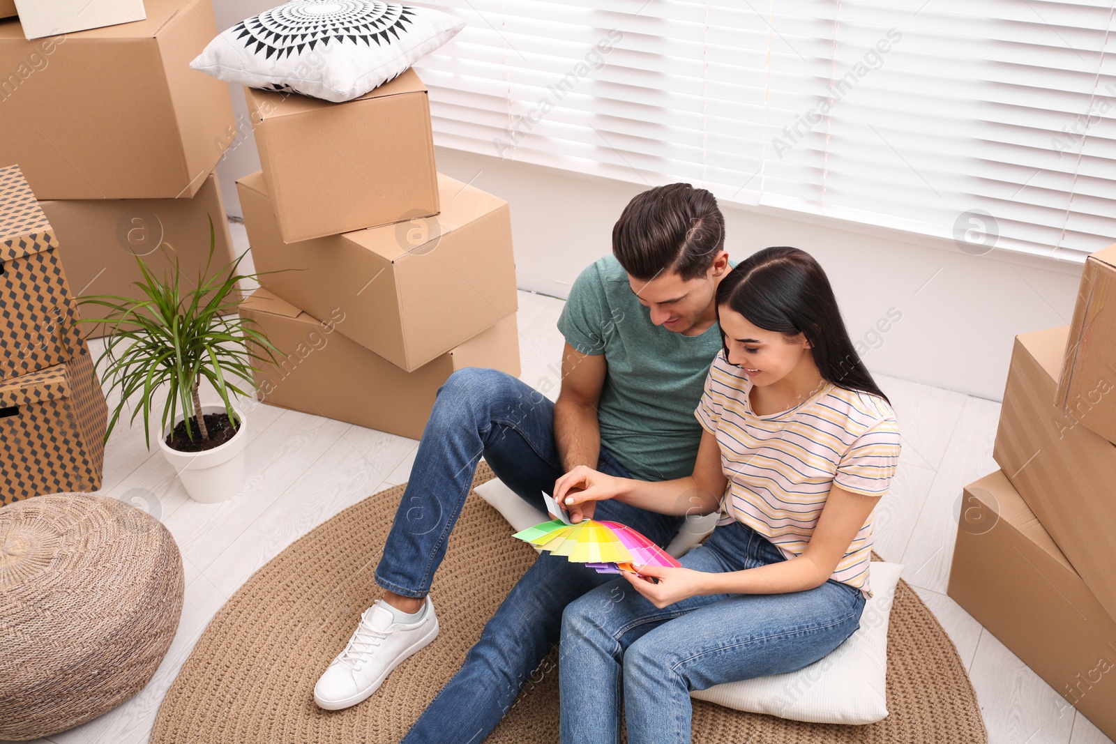 Photo of Happy couple with color palette samples in their new flat on moving day, above view