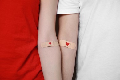 Blood donation concept. Couple with adhesive plasters on arms, closeup