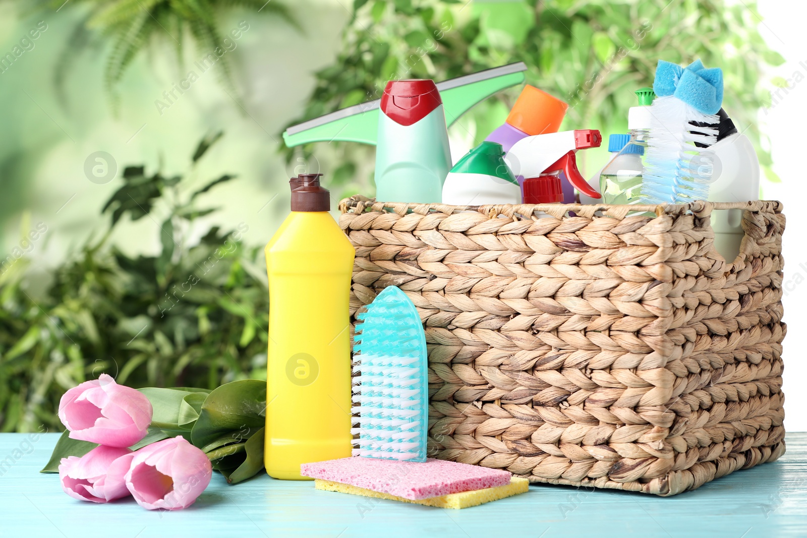 Photo of Spring flowers and cleaning supplies on light blue wooden table