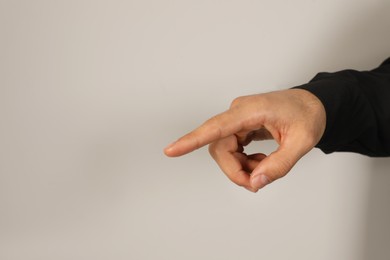 Photo of Man pointing at something on light background, closeup