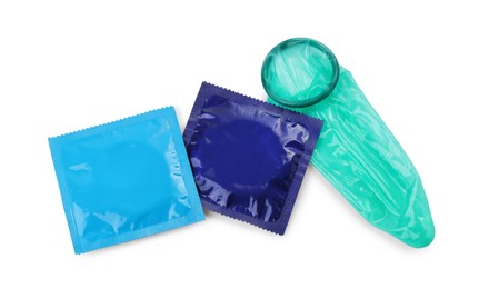 Photo of Unrolled condom and packages on white background, top view. Safe sex