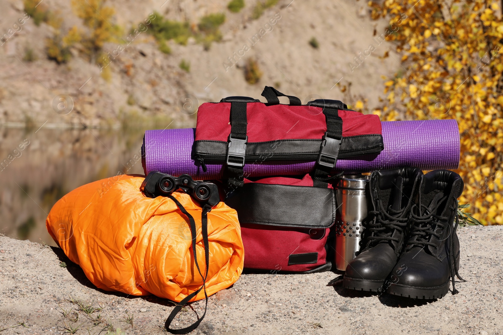 Photo of Set of camping equipment with sleeping bag on ground outdoors