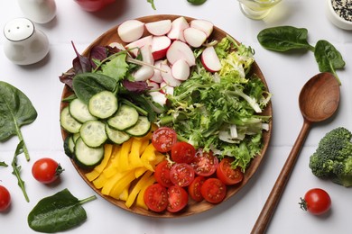 Vegetarian diet. Plate with tasty vegetables and spoon at white tiled table, flat lay