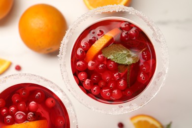 Tasty cranberry cocktail with oranges in glasses on white table, flat lay