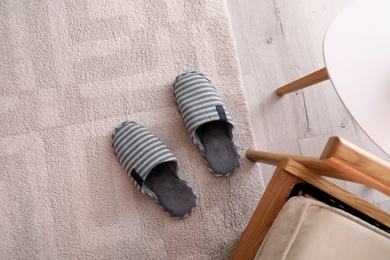 Photo of Pair of striped warm slippers on floor in room, flat lay