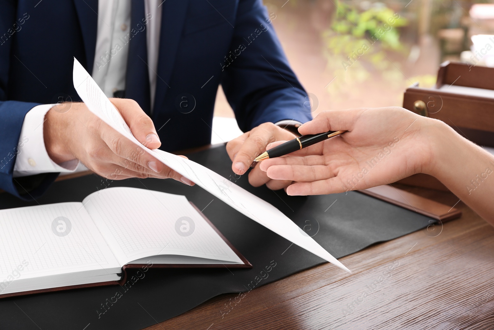 Photo of Lawyer working with client at table in office, focus on hands