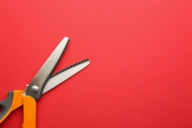 Pair of sharp scissors on color background, top view. Space for text