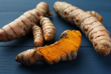 Raw turmeric roots on blue wooden table, closeup