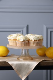 Photo of Delicious lemon cupcakes with white cream on table