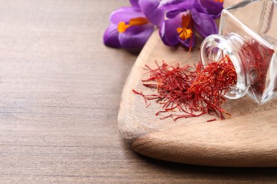 Photo of Dried saffron and crocus flowers on wooden table, closeup. Space for text