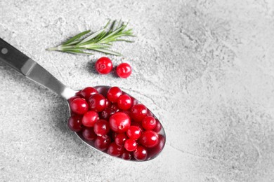 Photo of Fresh ripe cranberries in spoon on grey table, closeup. Space for text