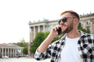 Photo of Young man talking on smartphone on city street