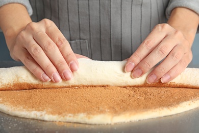 Woman making cinnamon rolls at table, closeup