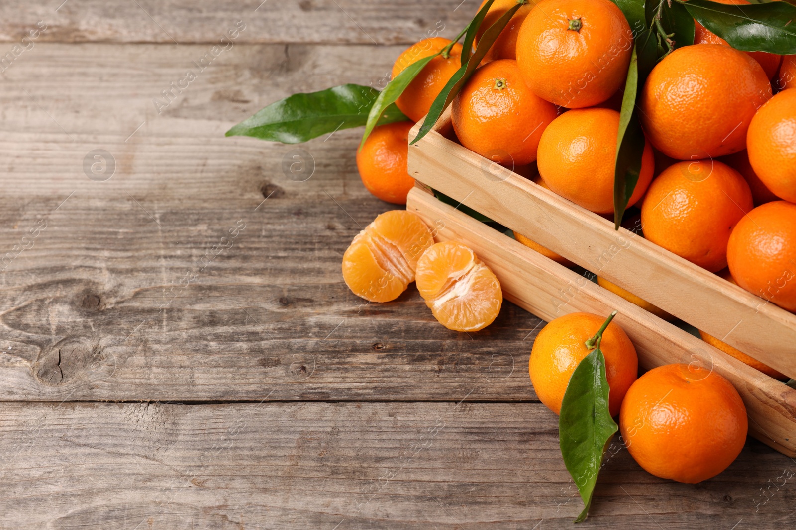 Photo of Delicious tangerines with leaves on wooden table. Space for text
