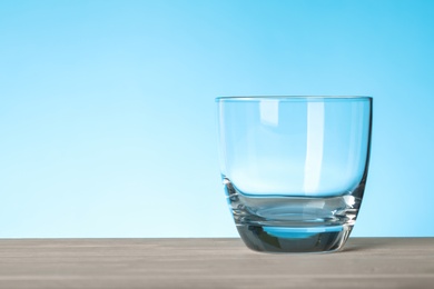 Photo of Empty glass on blue background, space for text