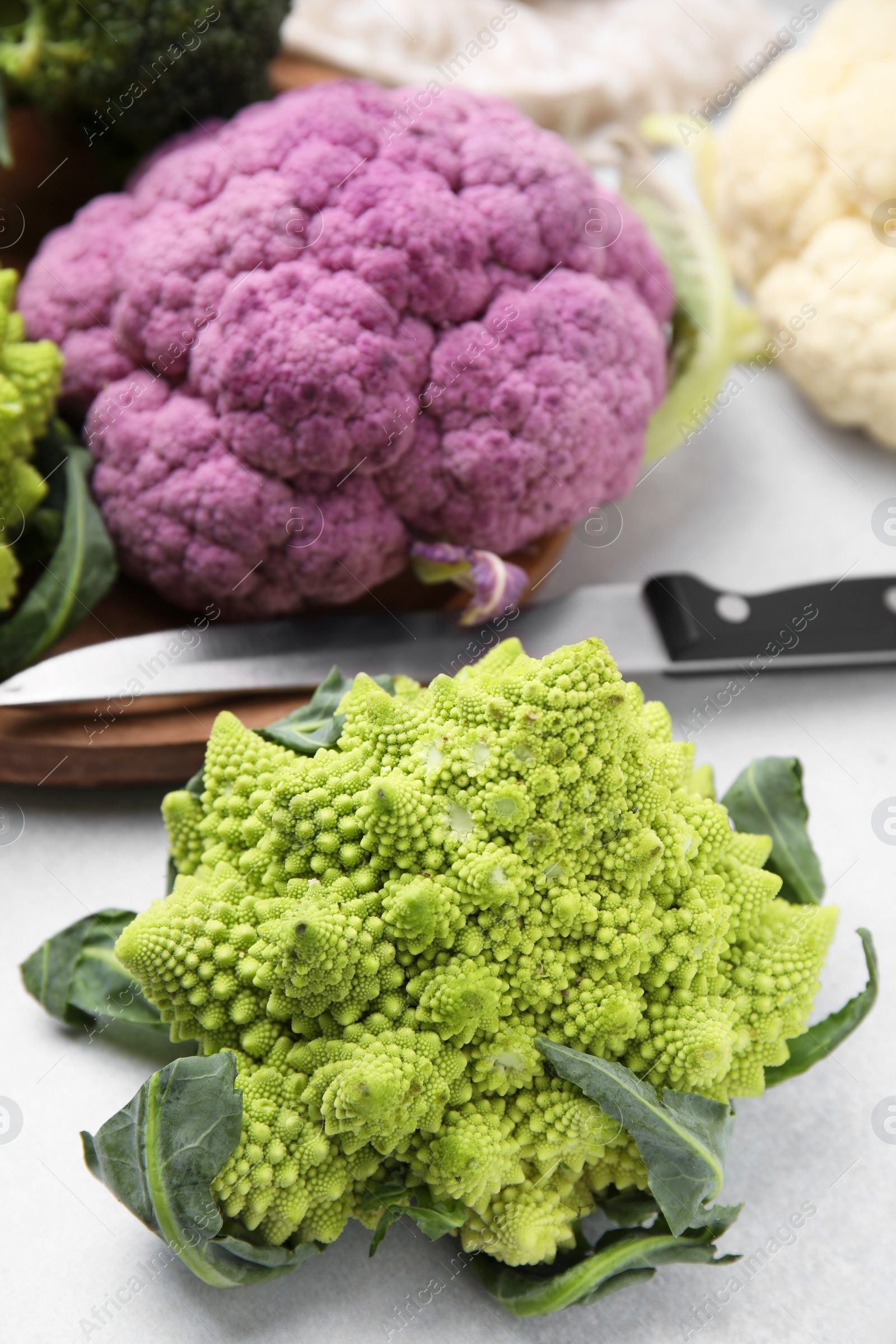 Photo of Different fresh cabbages and knife on white table