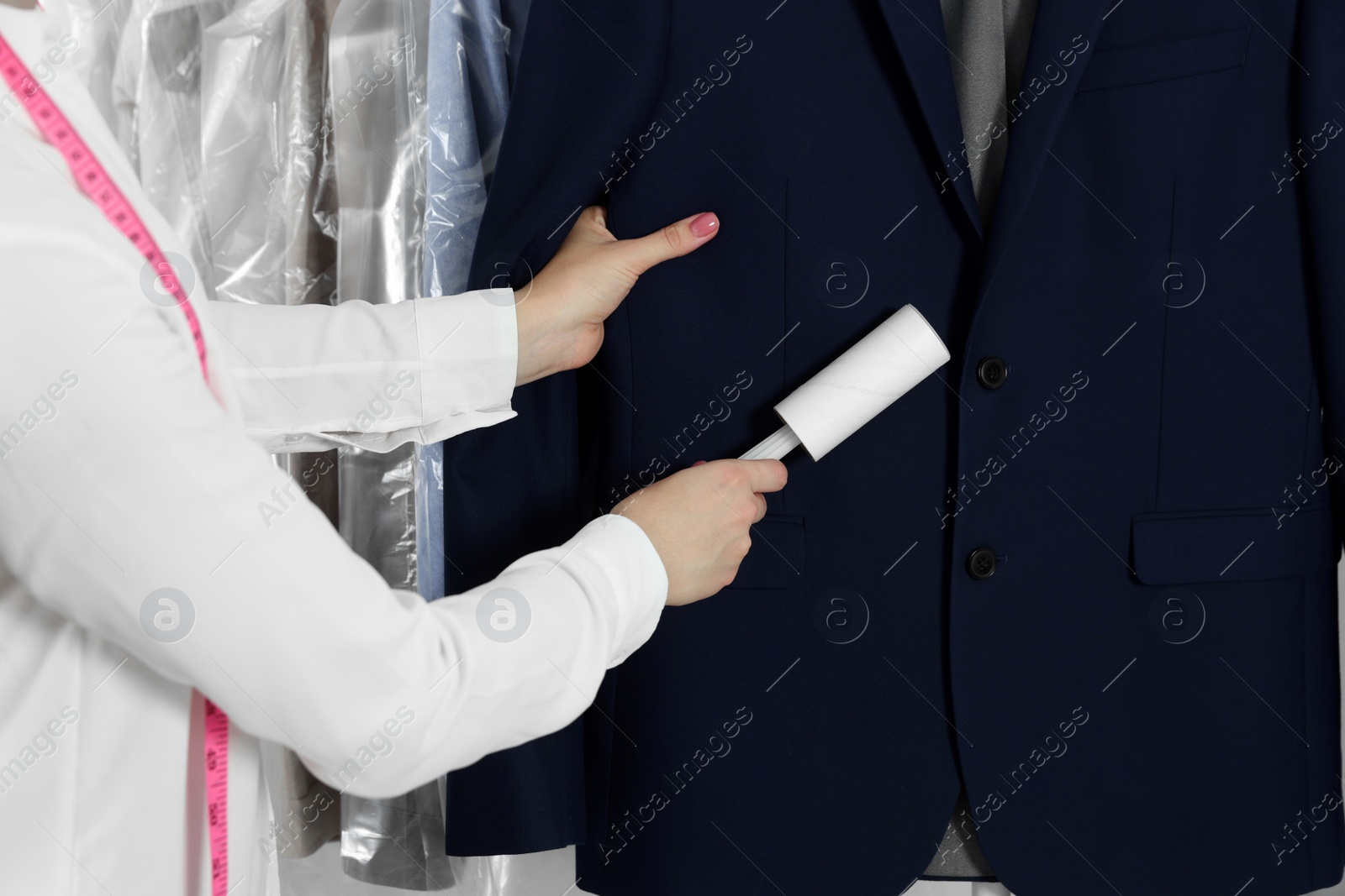 Photo of Woman using adhesive lint roller indoors, closeup. Dry-cleaning service