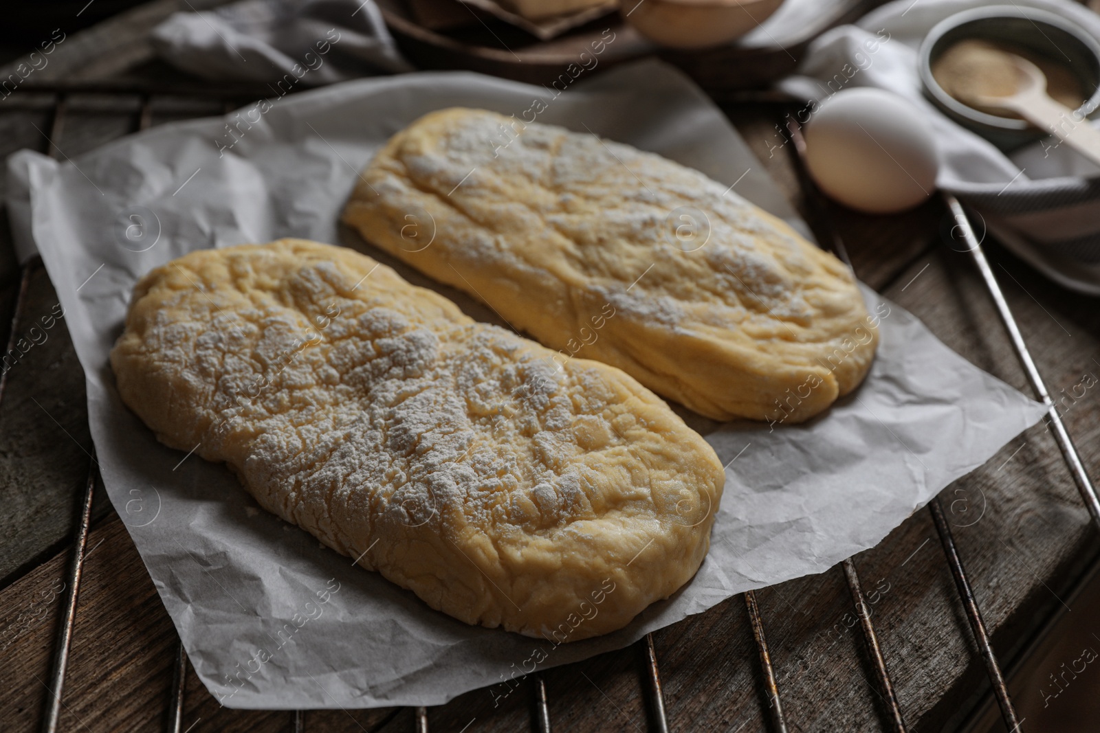 Photo of Raw dough for ciabatta and flour on wooden table