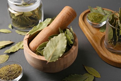 Photo of Whole and ground bay leaves on grey wooden table, closeup
