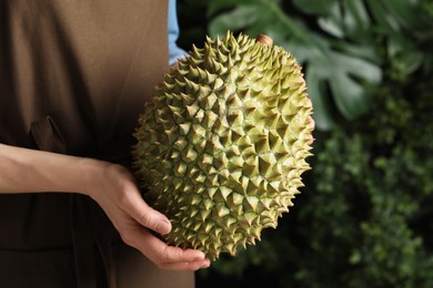 Photo of Woman holding fresh ripe durian outdoors, closeup