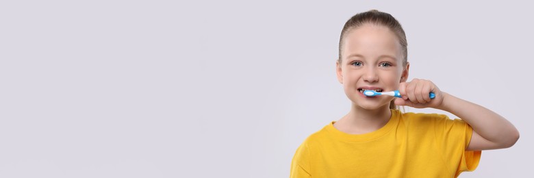 Happy girl brushing her teeth with toothbrush on white background. Banner design with space for text