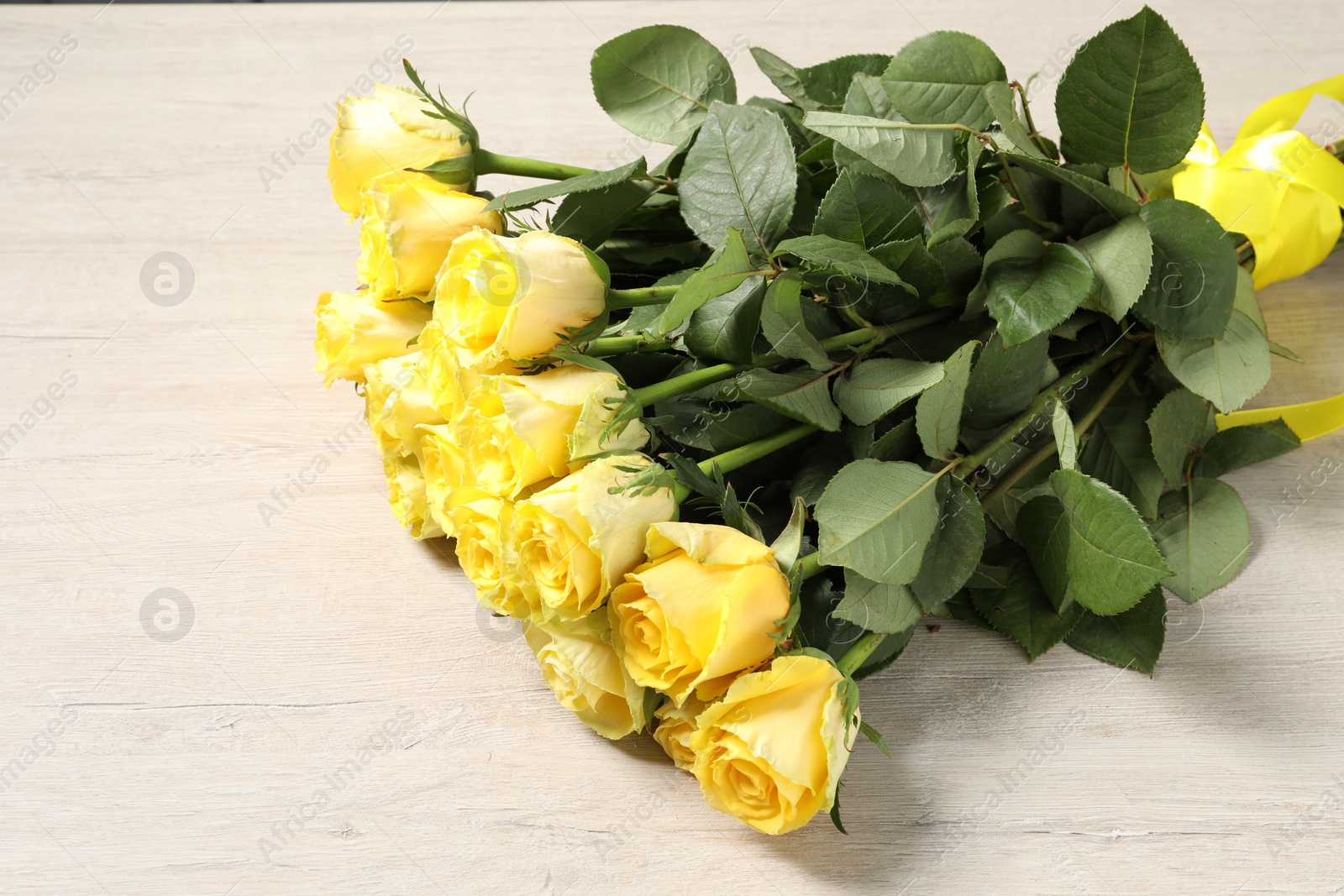 Photo of Beautiful bouquet of yellow roses on wooden table, above view. Space for text