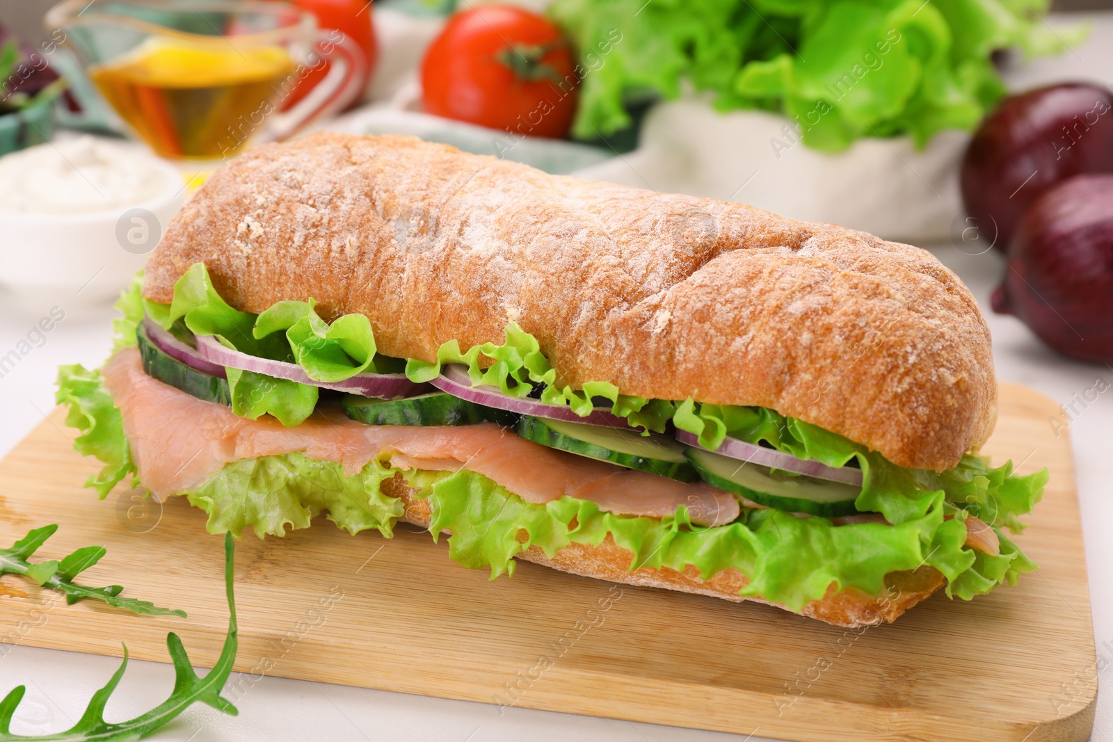 Photo of Delicious sandwich with fresh vegetables and salmon on wooden board, closeup