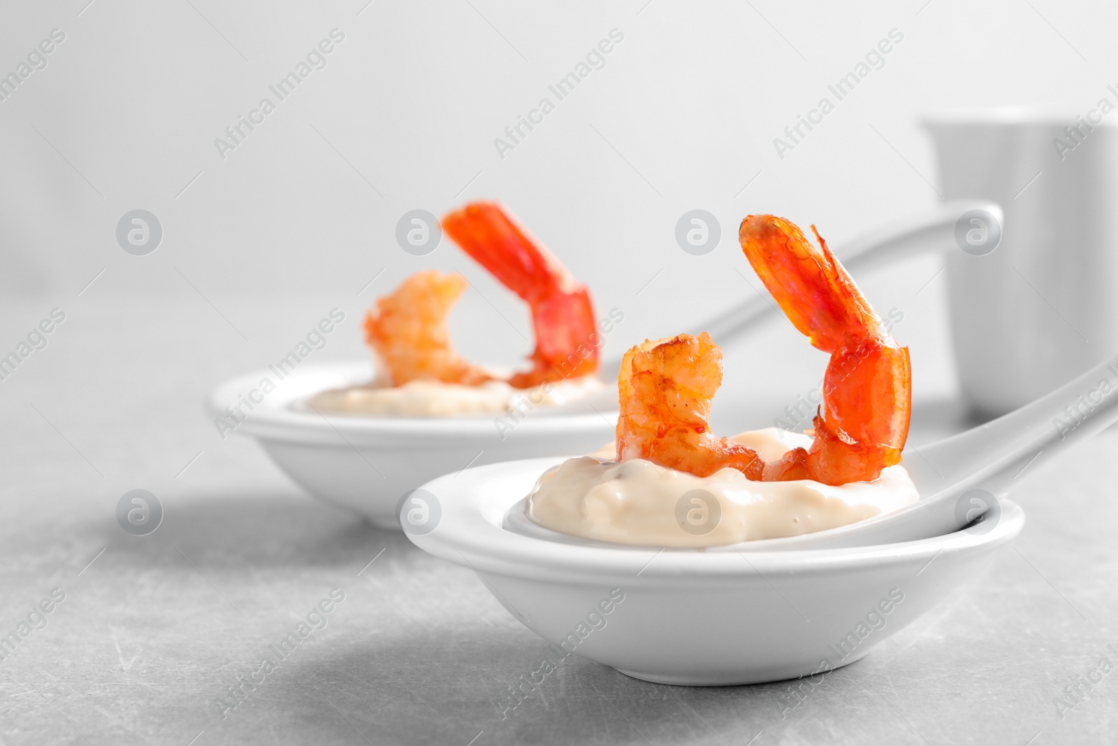 Photo of Delicious snacks with shrimp in spoons on grey background