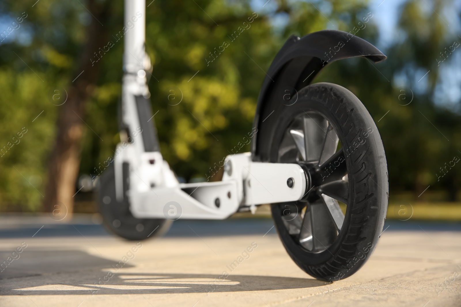 Photo of Modern kick scooter outdoors on sunny day, closeup