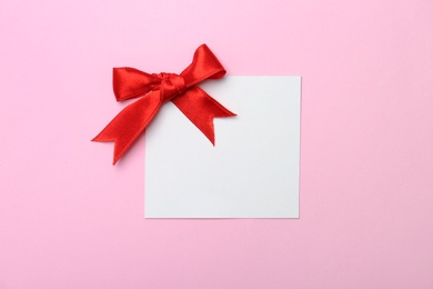 Photo of Blank gift tag with satin ribbon on color background, top view