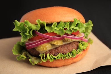 Photo of One tasty burger on dark table, closeup