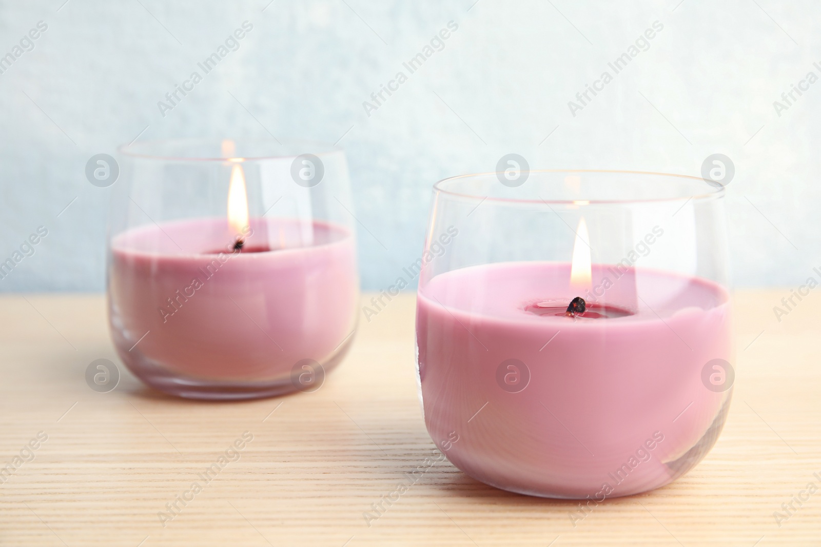 Photo of Burning wax candles in glass holders on wooden table