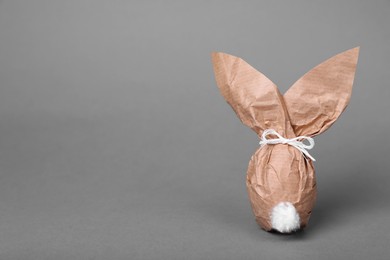 Photo of Easter bunny made of kraft paper and egg on grey background. Space for text