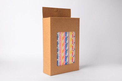 Box with many paper drinking straws on light grey background