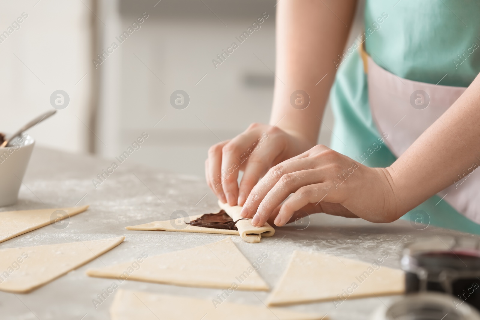 Photo of Woman preparing tasty croissants with chocolate paste on table, closeup