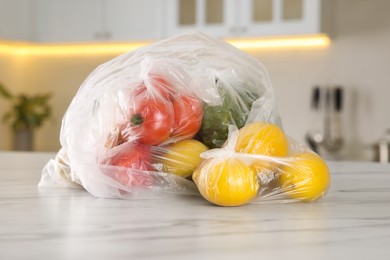 Plastic bags with different fresh products on white marble table in kitchen