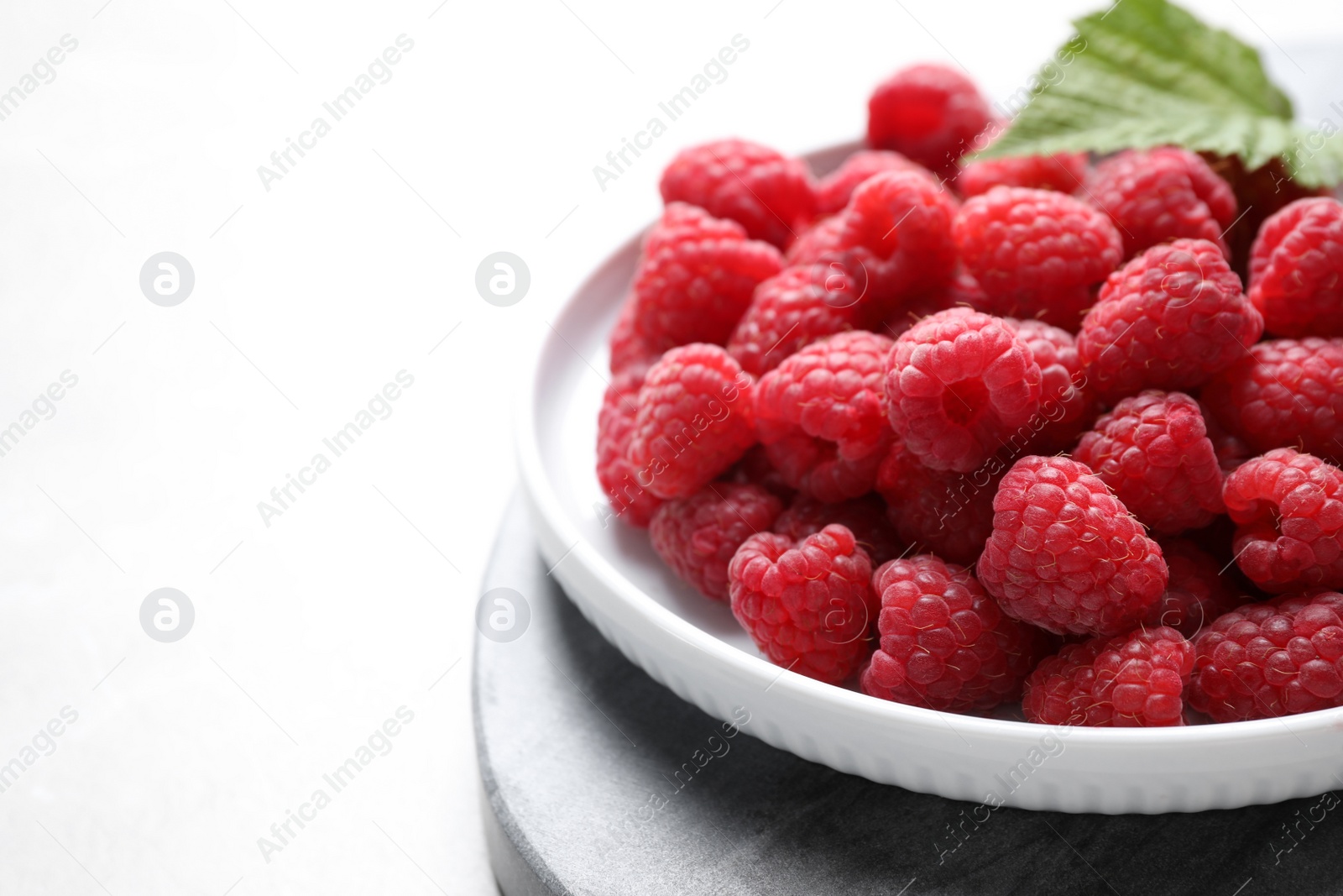 Photo of Delicious fresh ripe raspberries on white table, closeup