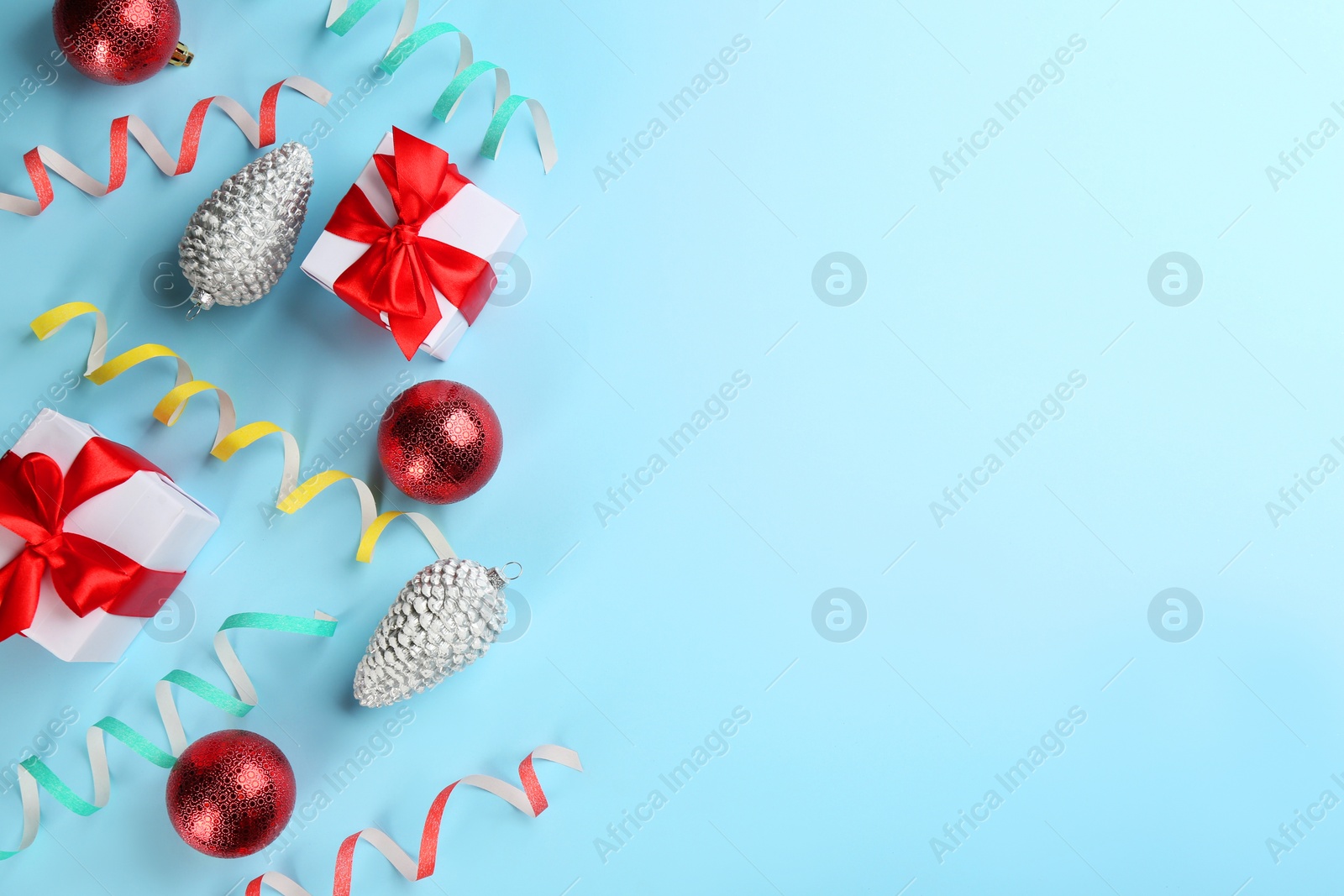 Photo of Flat lay composition with serpentine streamers and Christmas decor on light blue background. Space for text