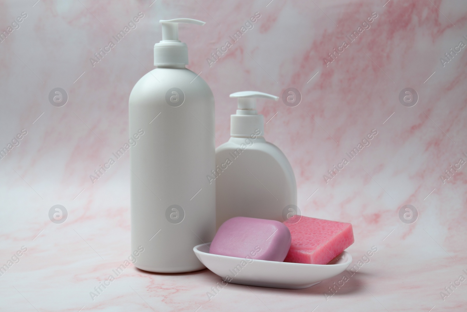 Photo of Soap bars and bottle dispensers on pink marble background
