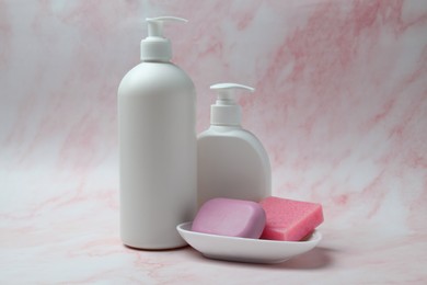 Photo of Soap bars and bottle dispensers on pink marble background