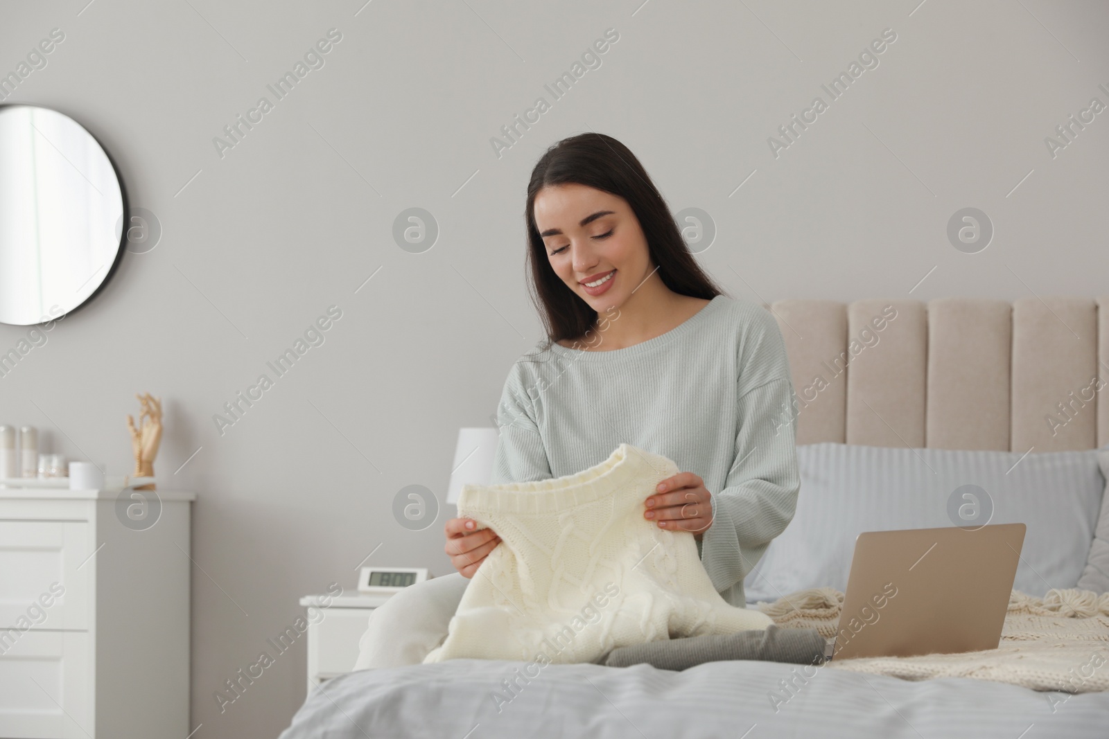 Photo of Young woman choosing clothes for work day at home. Morning routine