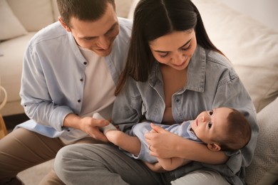 Photo of Happy family with cute baby on sofa at home