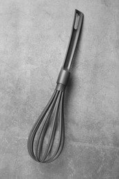 Plastic whisk on gray table, top view